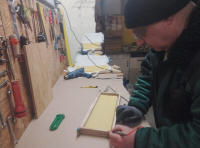 Imker bestückt Rähmchen in der Werkstatt für die Honigräume